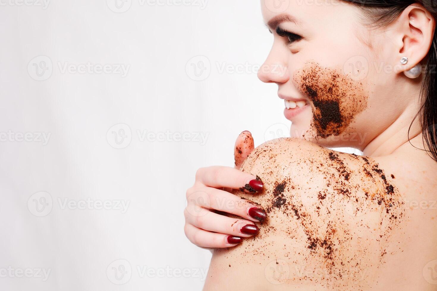 morena mujer limpia el piel de el cuerpo café fregar foto