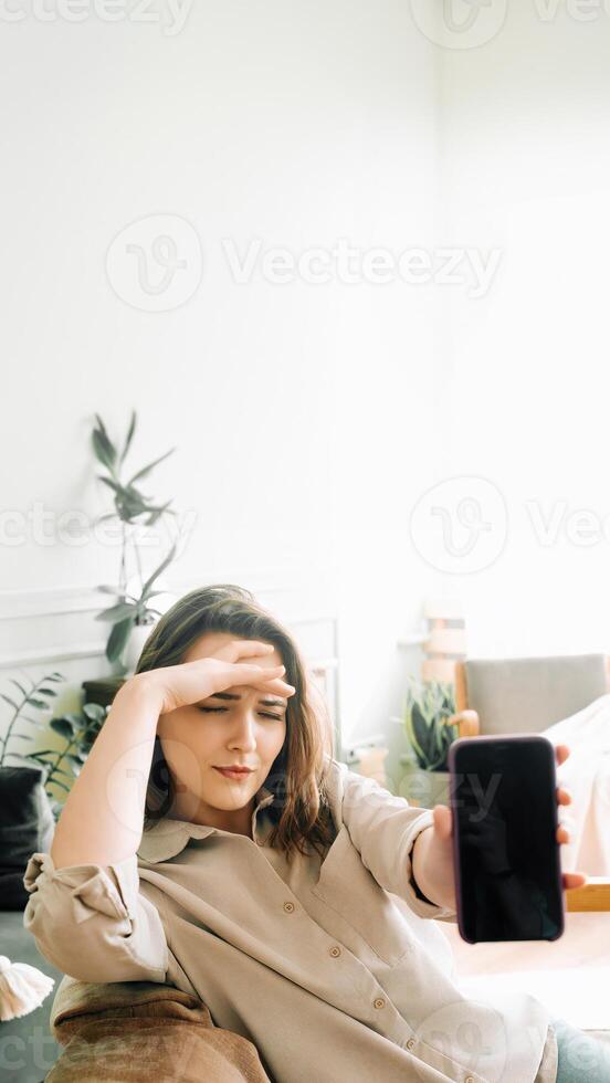 Unhappy Millennial Woman Holding Smartphone with Blank Screen, Expressing Stress and Discontentment in Modern Technology Use photo