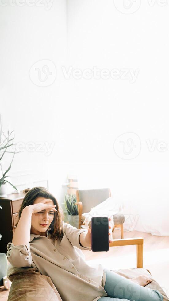 Stressed Millennial Woman Displays Smartphone with Blank Screen, Expressing Unhappiness and Discontent in Modern Technology Use photo