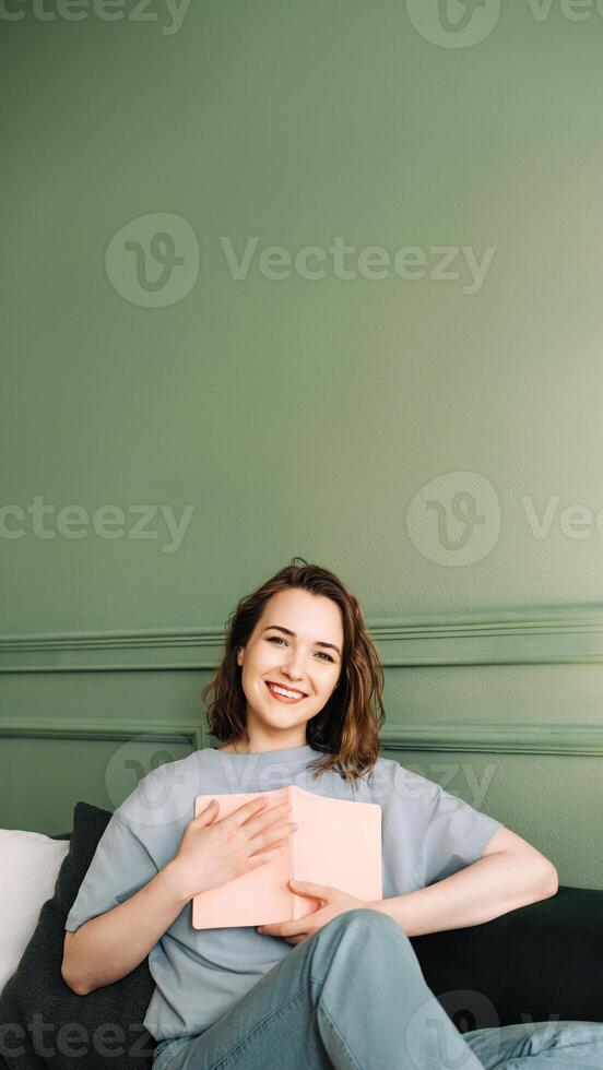 Joyful Middle-Aged Woman Holding a Book Close. Smiling Lady Embracing a Book with Cheerful Expression. Happiness and Literature Connection. Middle-Aged Woman Grasping a Book photo