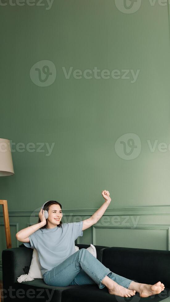 Happy young woman in wireless headphones listening to music while dancing. Rhythmic Euphoria. Joyful Woman Grooving to Music in Wireless Headphones. Musical Elation. Dance of Joy photo