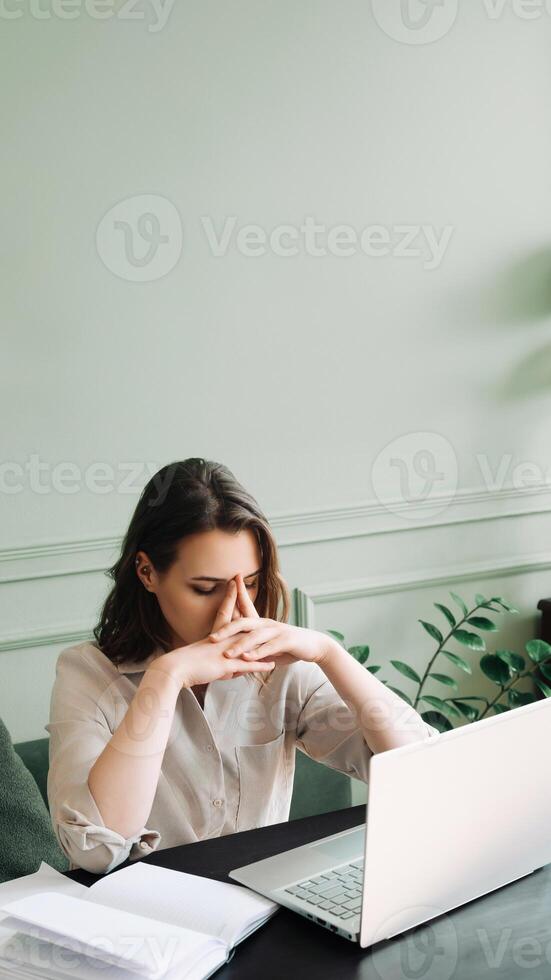 Fatigued Young Woman, Overworked and Dejected, Gazing at Computer Screen in Distress. Overwhelmed Young Woman Struggling at Computer Desk, Battling Overexertion and Weariness photo