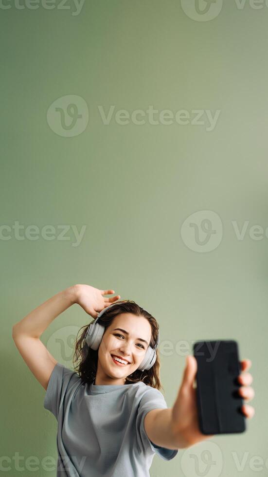 A young woman wearing wireless headphones listening to music, dancing. Energetic Beats. Young Lady Enjoys Music, Moves to the Rhythm. Dancing Melodies. Woman Grooving with Wireless Headphones photo
