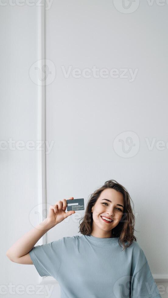 Positive Middle-Aged Woman Showing Credit Card in Close-up Studio Shot. Happy Middle-Aged Lady Presenting Credit Card, Studio Close-up. Middle-Aged Woman Grinning, Holding Credit Card photo