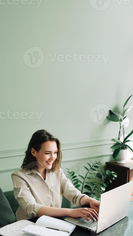 Energetic Young Woman Multi-Tasking. Typing on Laptop and Video Calling in Stylish Indoor Setting photo