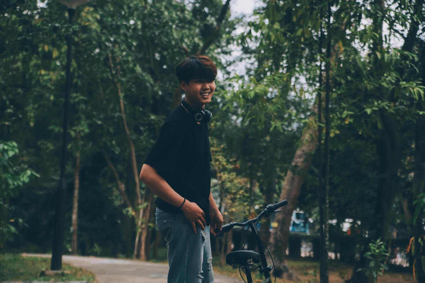 joven hermoso barbado hombre tomando un descanso mientras de viaje el ciudad con su bicicleta utilizando su digital tableta mirando lejos pensativamente foto