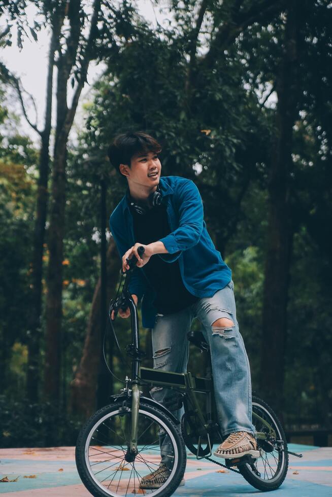 joven hermoso barbado hombre tomando un descanso mientras de viaje el ciudad con su bicicleta utilizando su digital tableta mirando lejos pensativamente foto