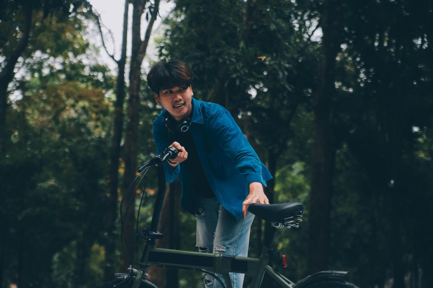 Young handsome bearded man taking a break while travelling the city with his bicycle using his digital tablet looking away thoughtfully photo