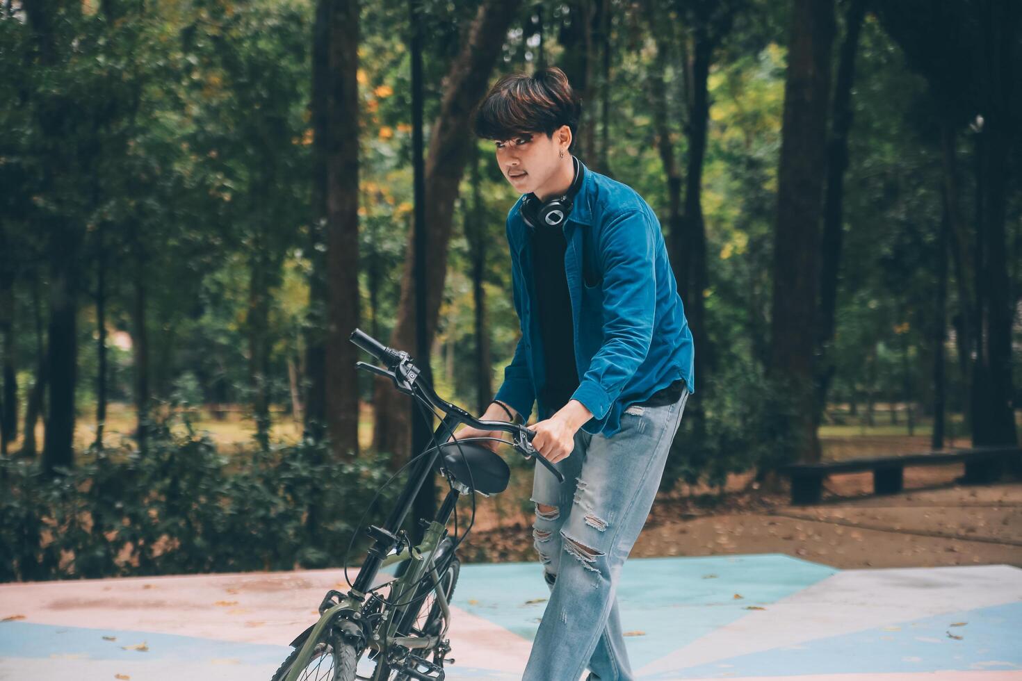 joven hermoso barbado hombre tomando un descanso mientras de viaje el ciudad con su bicicleta utilizando su digital tableta mirando lejos pensativamente foto