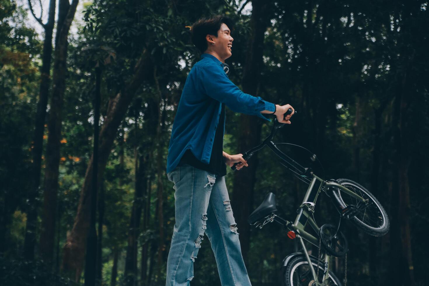 Young handsome bearded man taking a break while travelling the city with his bicycle using his digital tablet looking away thoughtfully photo