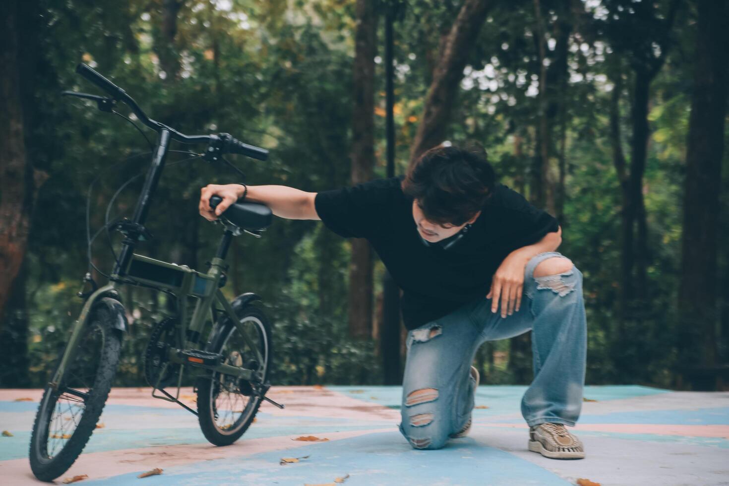 Young handsome bearded man taking a break while travelling the city with his bicycle using his digital tablet looking away thoughtfully photo