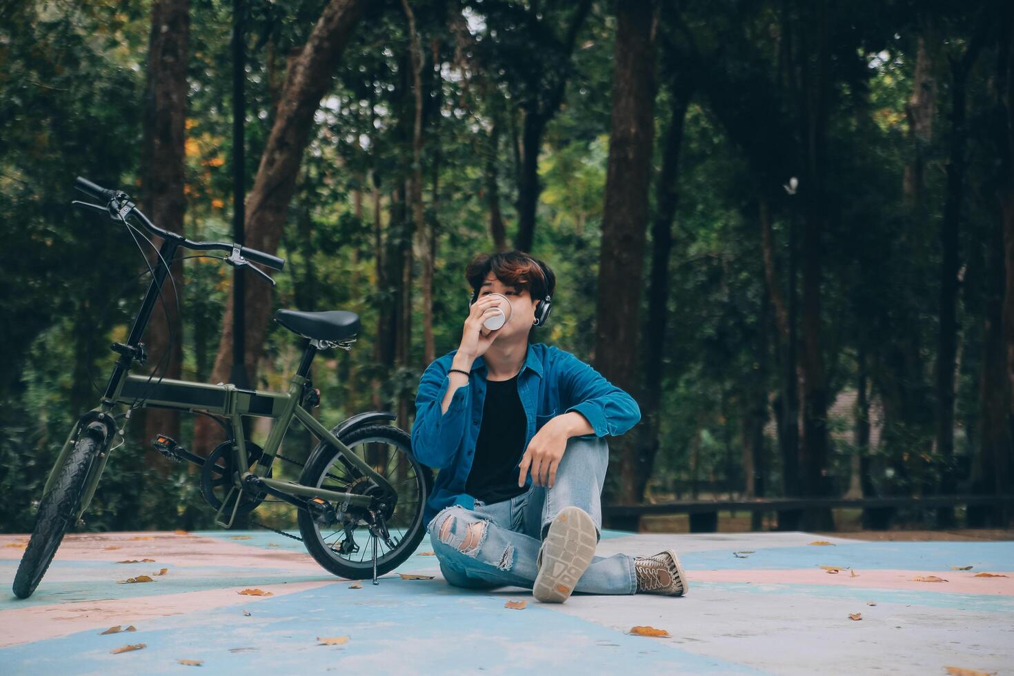 Young handsome bearded man taking a break while travelling the city with his bicycle using his digital tablet looking away thoughtfully photo