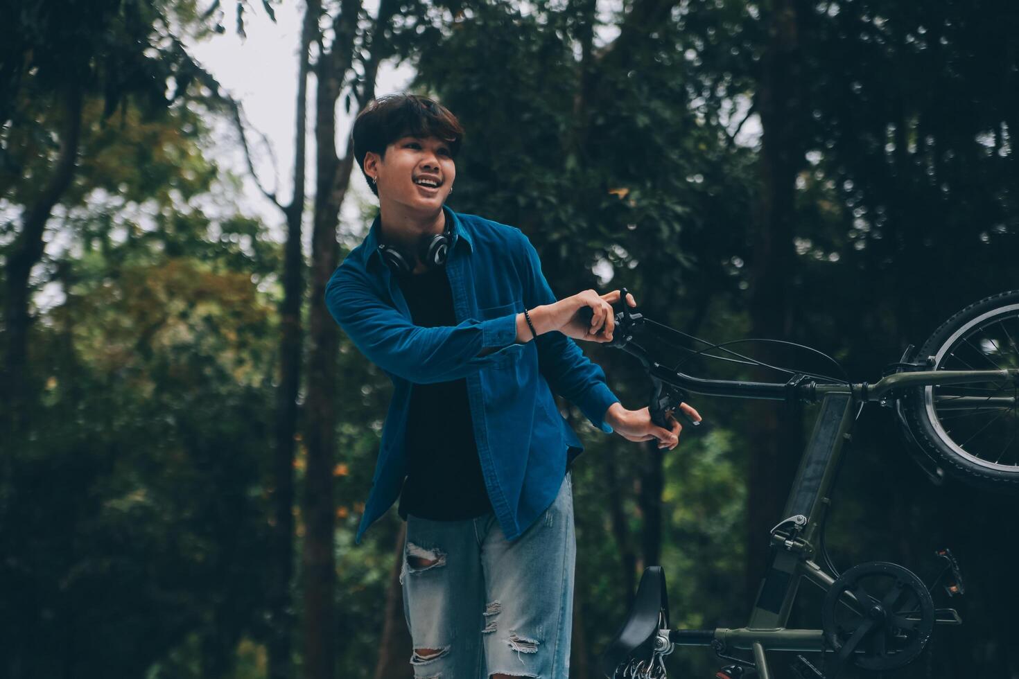 Young handsome bearded man taking a break while travelling the city with his bicycle using his digital tablet looking away thoughtfully photo