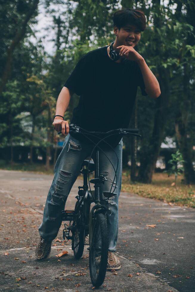Young handsome bearded man taking a break while travelling the city with his bicycle using his digital tablet looking away thoughtfully photo