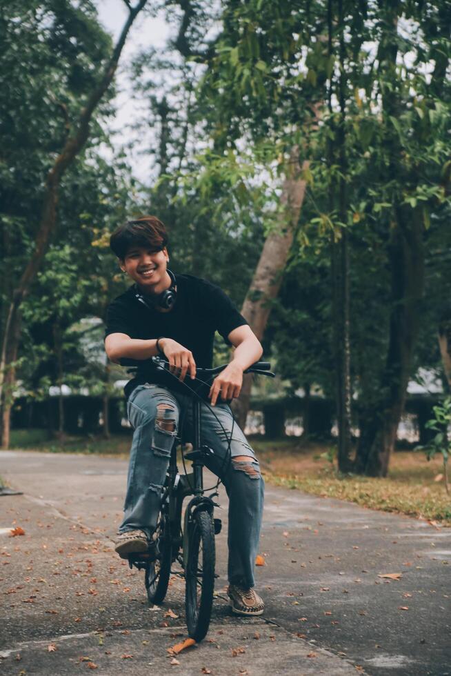 Young handsome bearded man taking a break while travelling the city with his bicycle using his digital tablet looking away thoughtfully photo