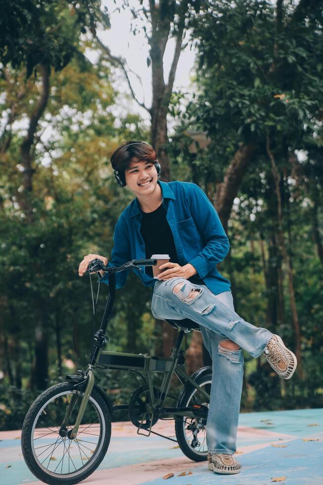 Young handsome bearded man taking a break while travelling the city with his bicycle using his digital tablet looking away thoughtfully photo
