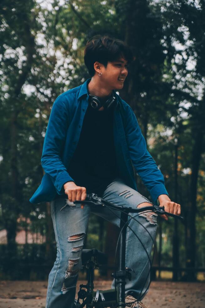 Young handsome bearded man taking a break while travelling the city with his bicycle using his digital tablet looking away thoughtfully photo