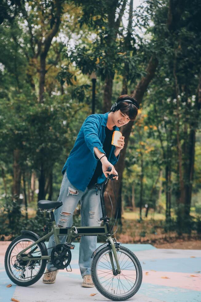 Young handsome bearded man taking a break while travelling the city with his bicycle using his digital tablet looking away thoughtfully photo