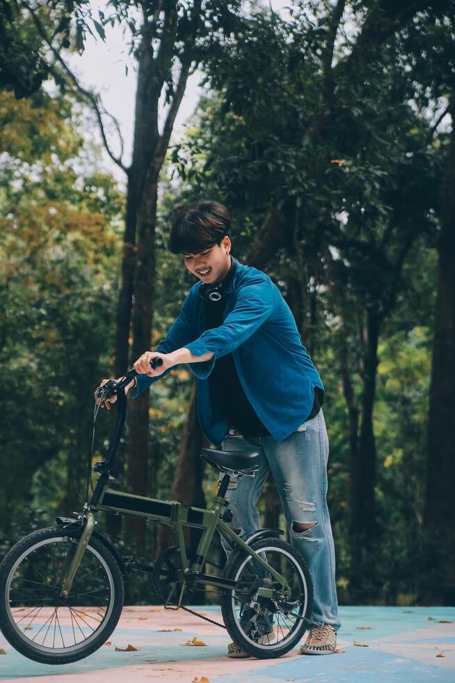 Young handsome bearded man taking a break while travelling the city with his bicycle using his digital tablet looking away thoughtfully photo