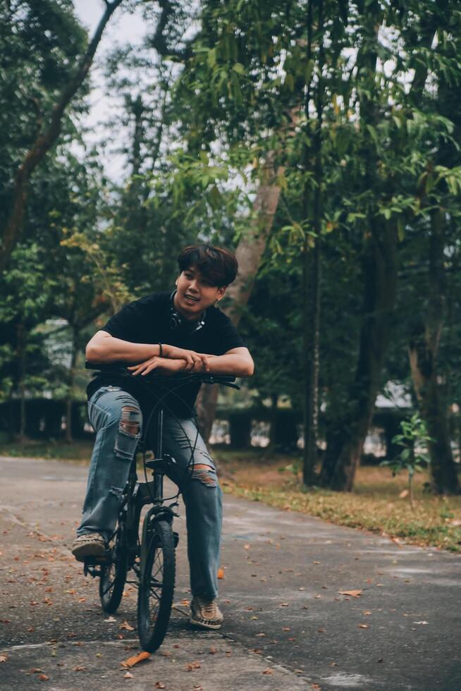 Young handsome bearded man taking a break while travelling the city with his bicycle using his digital tablet looking away thoughtfully photo