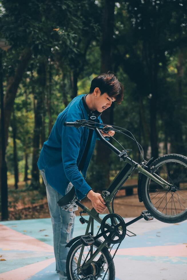 Young handsome bearded man taking a break while travelling the city with his bicycle using his digital tablet looking away thoughtfully photo