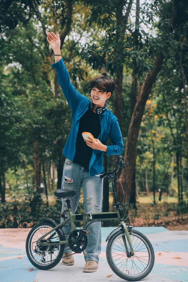 Young handsome bearded man taking a break while travelling the city with his bicycle using his digital tablet looking away thoughtfully photo