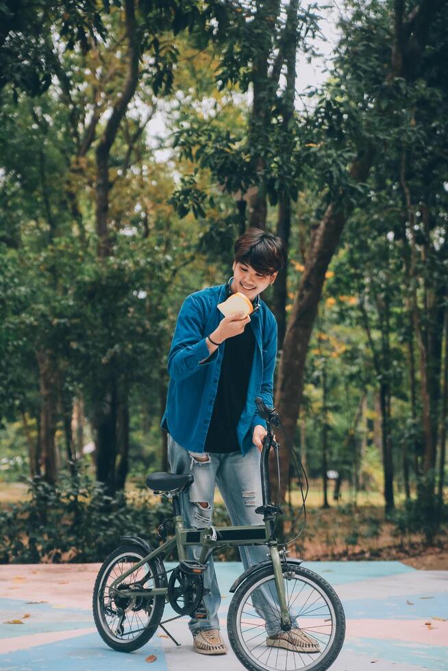 Young handsome bearded man taking a break while travelling the city with his bicycle using his digital tablet looking away thoughtfully photo
