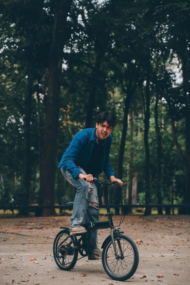 Young handsome bearded man taking a break while travelling the city with his bicycle using his digital tablet looking away thoughtfully photo