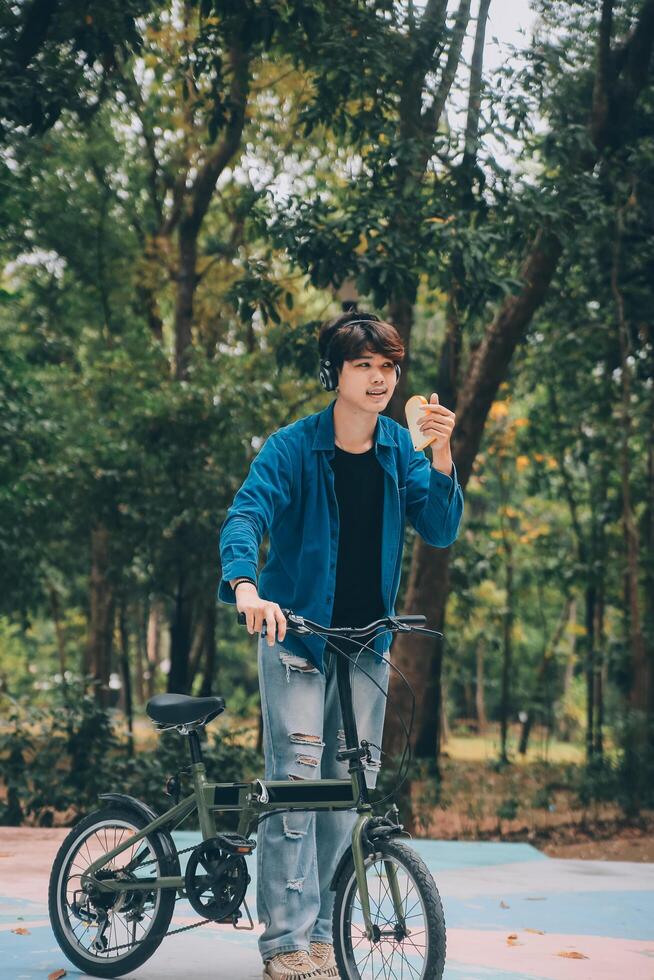 Young handsome bearded man taking a break while travelling the city with his bicycle using his digital tablet looking away thoughtfully photo