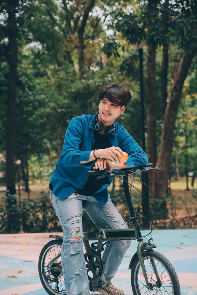 Young handsome bearded man taking a break while travelling the city with his bicycle using his digital tablet looking away thoughtfully photo