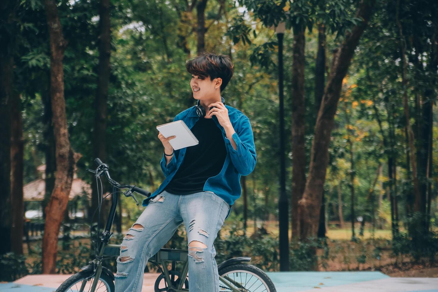 Young handsome bearded man taking a break while travelling the city with his bicycle using his digital tablet looking away thoughtfully photo