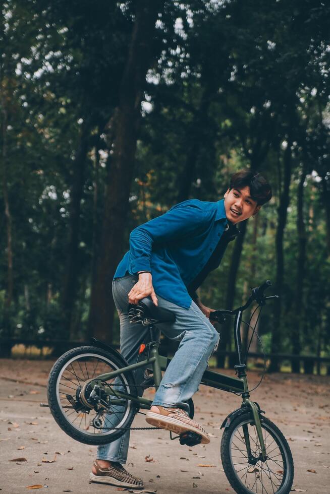 Young handsome bearded man taking a break while travelling the city with his bicycle using his digital tablet looking away thoughtfully photo