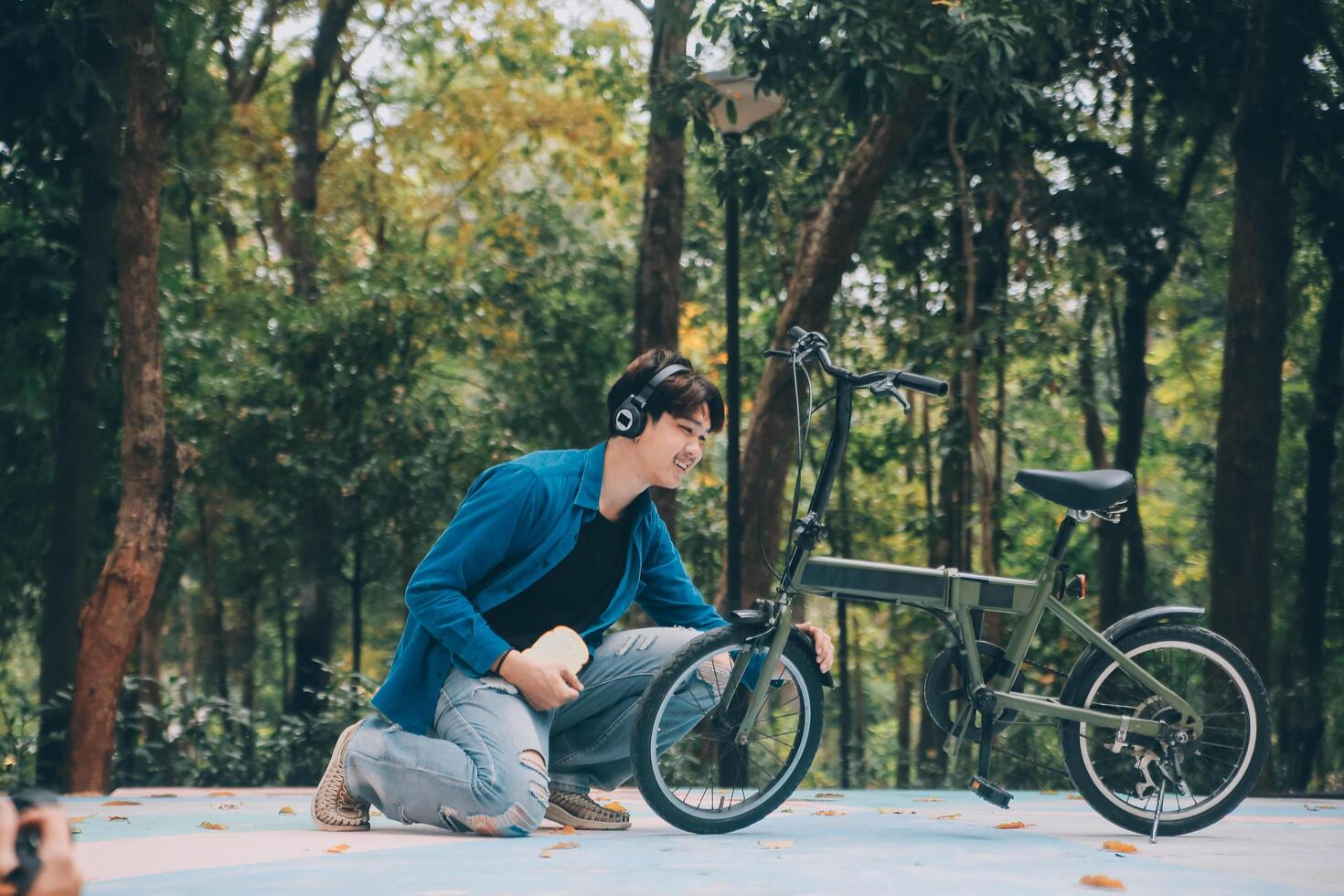 Young handsome bearded man taking a break while travelling the city with his bicycle using his digital tablet looking away thoughtfully photo