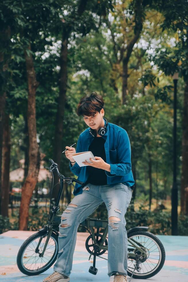 Young handsome bearded man taking a break while travelling the city with his bicycle using his digital tablet looking away thoughtfully photo