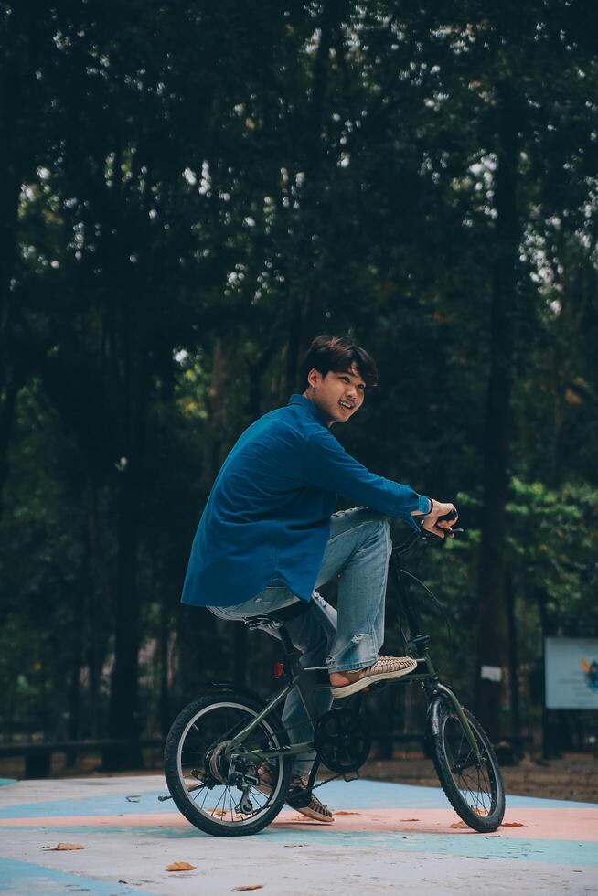 Young handsome bearded man taking a break while travelling the city with his bicycle using his digital tablet looking away thoughtfully photo