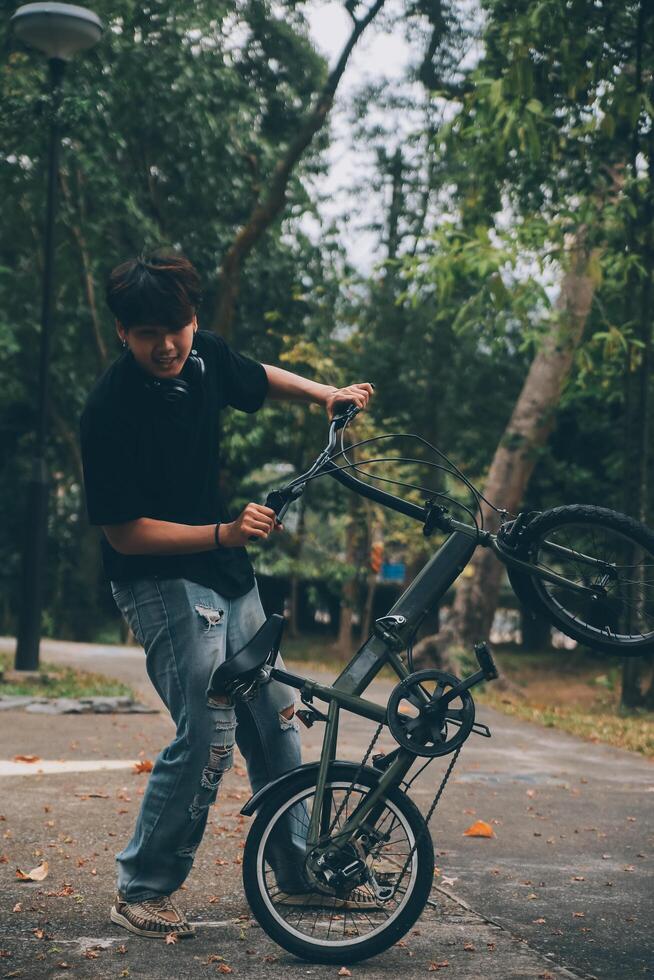 Young handsome bearded man taking a break while travelling the city with his bicycle using his digital tablet looking away thoughtfully photo