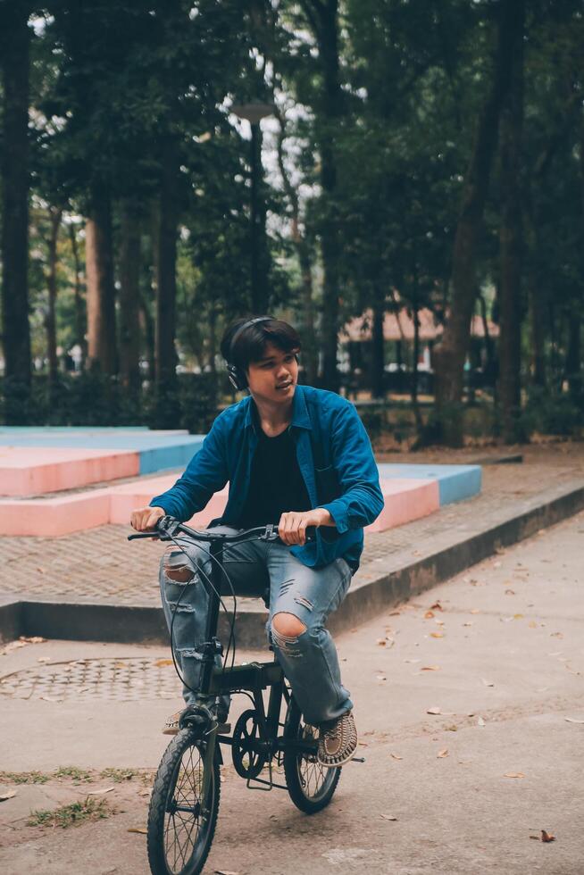 Young handsome bearded man taking a break while travelling the city with his bicycle using his digital tablet looking away thoughtfully photo