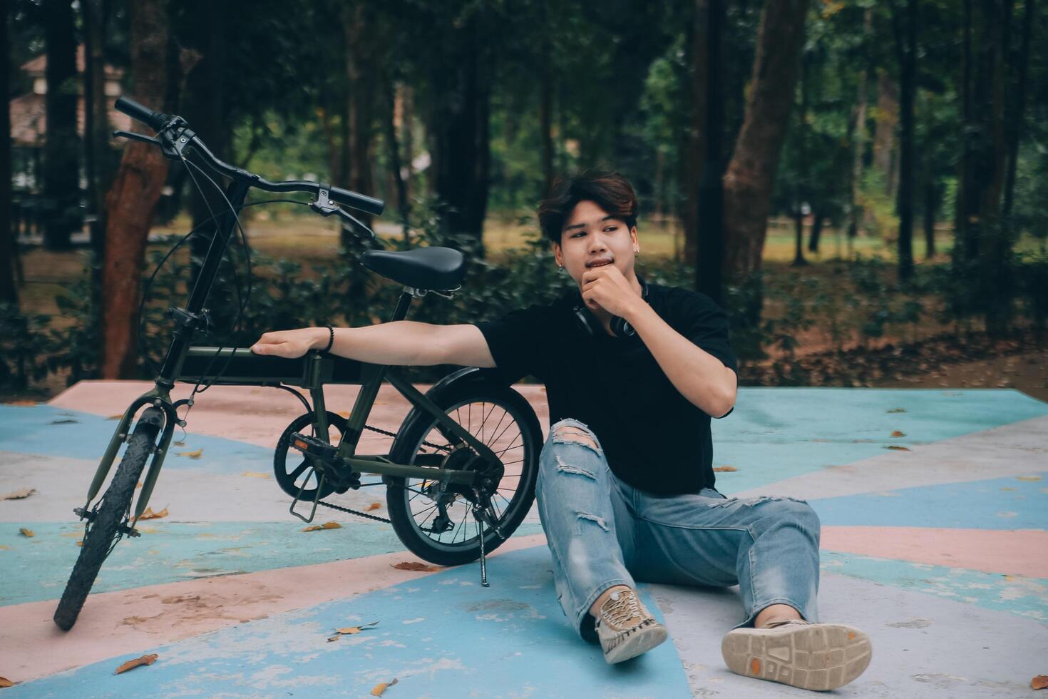 Young handsome bearded man taking a break while travelling the city with his bicycle using his digital tablet looking away thoughtfully photo