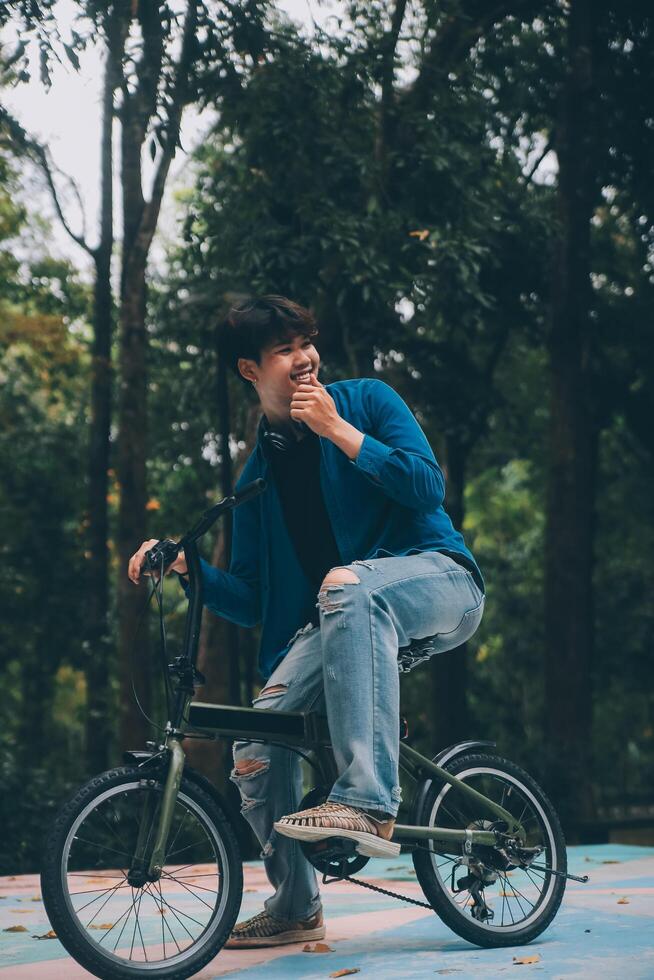 Young handsome bearded man taking a break while travelling the city with his bicycle using his digital tablet looking away thoughtfully photo