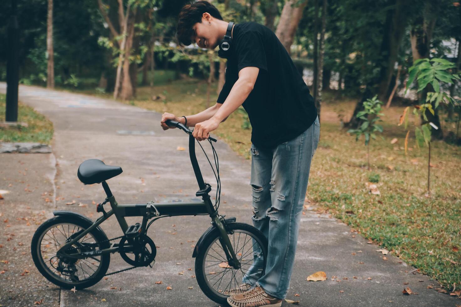 Young handsome bearded man taking a break while travelling the city with his bicycle using his digital tablet looking away thoughtfully photo