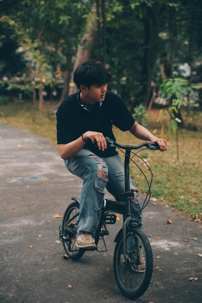 Young handsome bearded man taking a break while travelling the city with his bicycle using his digital tablet looking away thoughtfully photo