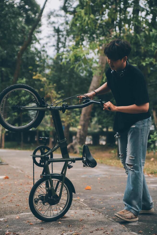 Young handsome bearded man taking a break while travelling the city with his bicycle using his digital tablet looking away thoughtfully photo