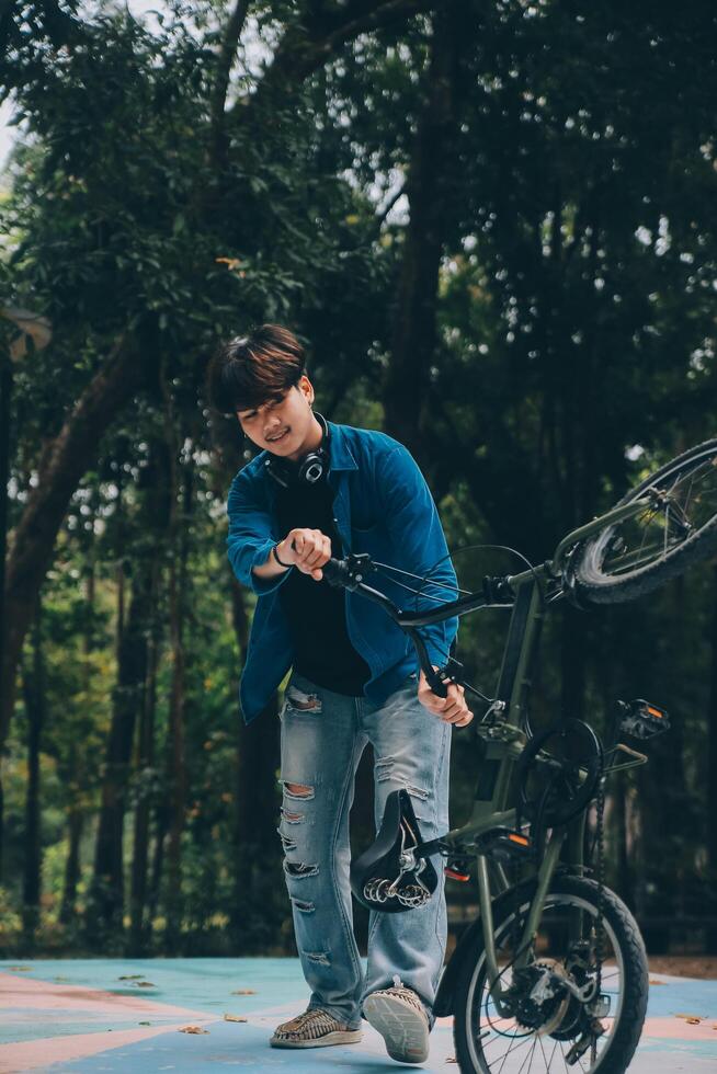 joven hermoso barbado hombre tomando un descanso mientras de viaje el ciudad con su bicicleta utilizando su digital tableta mirando lejos pensativamente foto