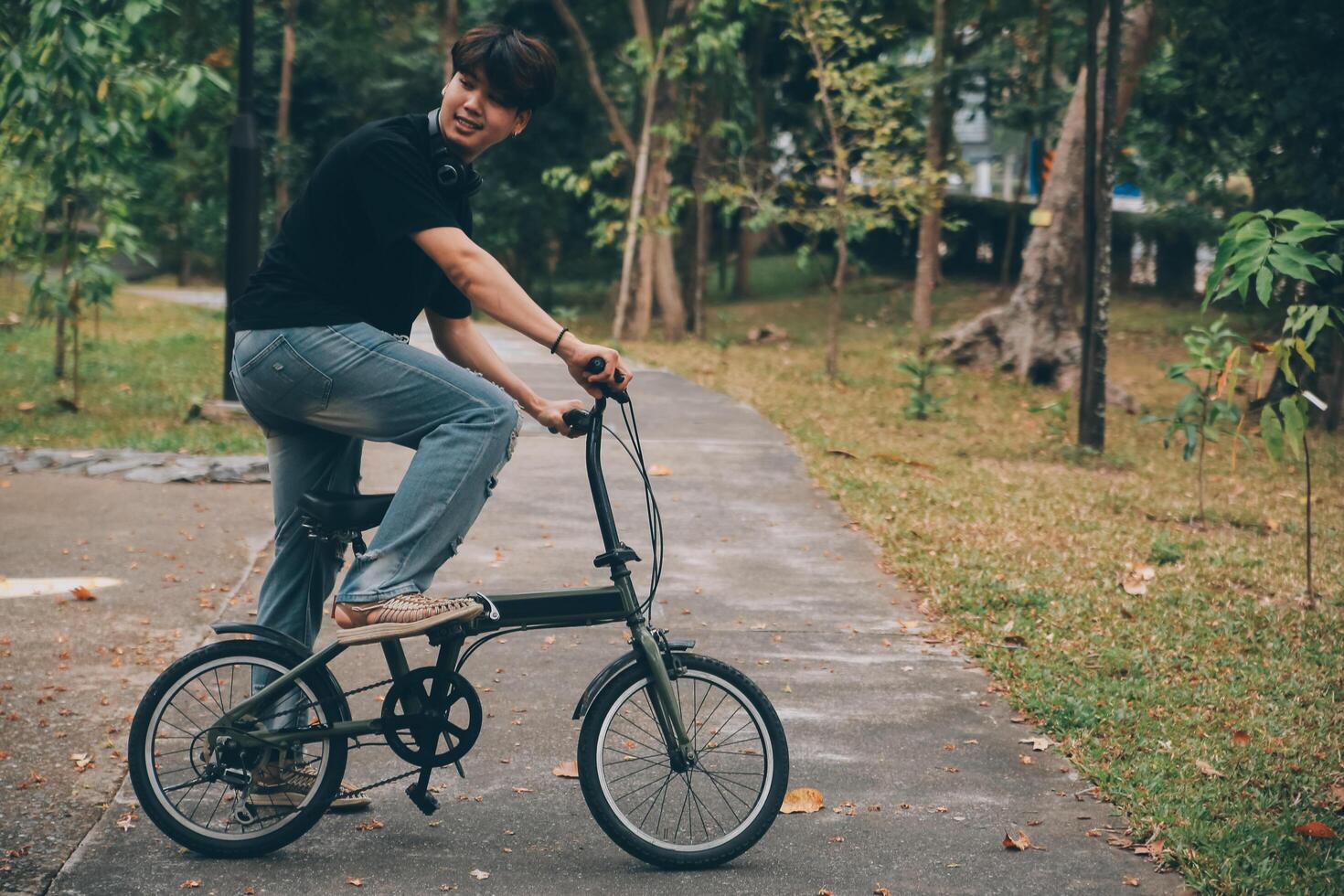 Young handsome bearded man taking a break while travelling the city with his bicycle using his digital tablet looking away thoughtfully photo