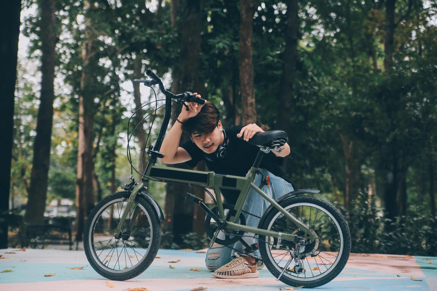 Young handsome bearded man taking a break while travelling the city with his bicycle using his digital tablet looking away thoughtfully photo