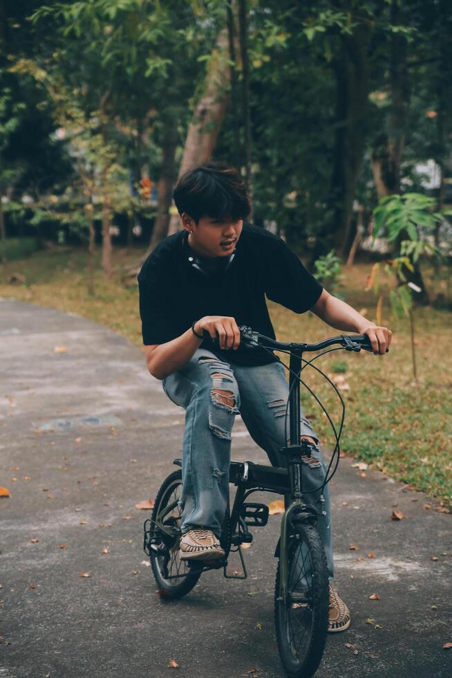 Young handsome bearded man taking a break while travelling the city with his bicycle using his digital tablet looking away thoughtfully photo