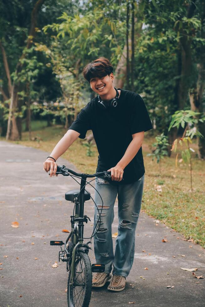 Young handsome bearded man taking a break while travelling the city with his bicycle using his digital tablet looking away thoughtfully photo