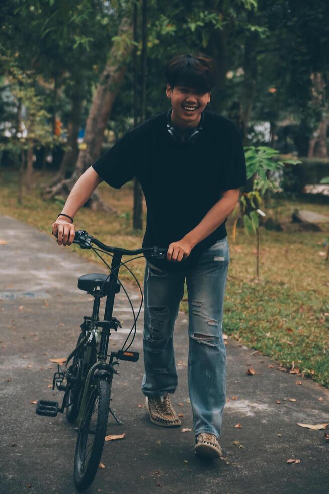 Young handsome bearded man taking a break while travelling the city with his bicycle using his digital tablet looking away thoughtfully photo