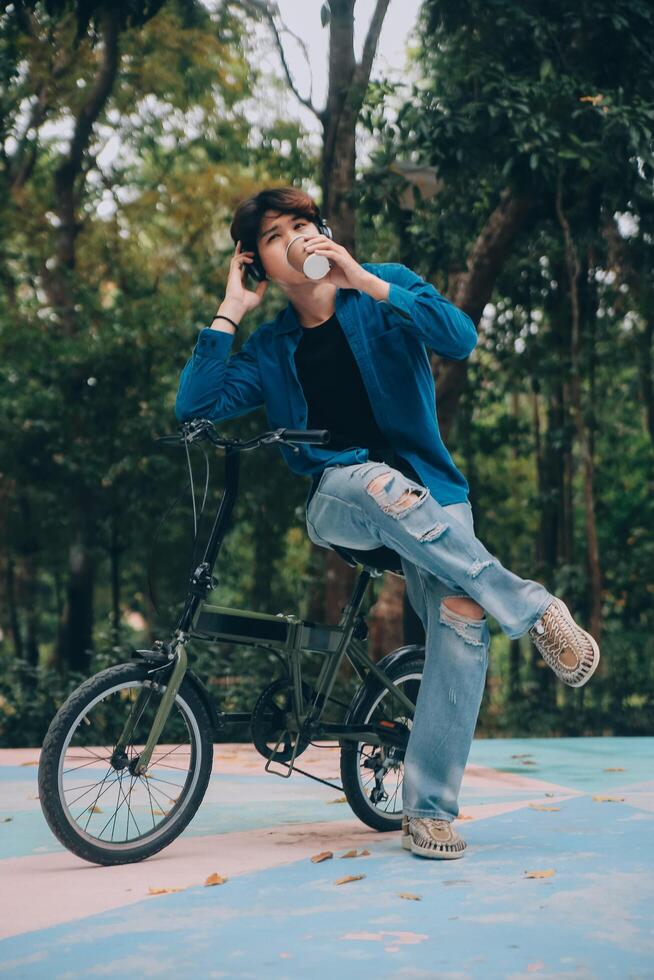 Young handsome bearded man taking a break while travelling the city with his bicycle using his digital tablet looking away thoughtfully photo