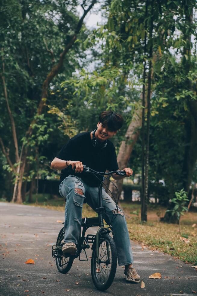 joven hermoso barbado hombre tomando un descanso mientras de viaje el ciudad con su bicicleta utilizando su digital tableta mirando lejos pensativamente foto